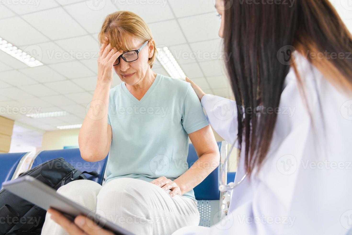 kvinnlig läkare ger råd till den gamla kvinnan patienten genom en tablett på sjukhuset. foto