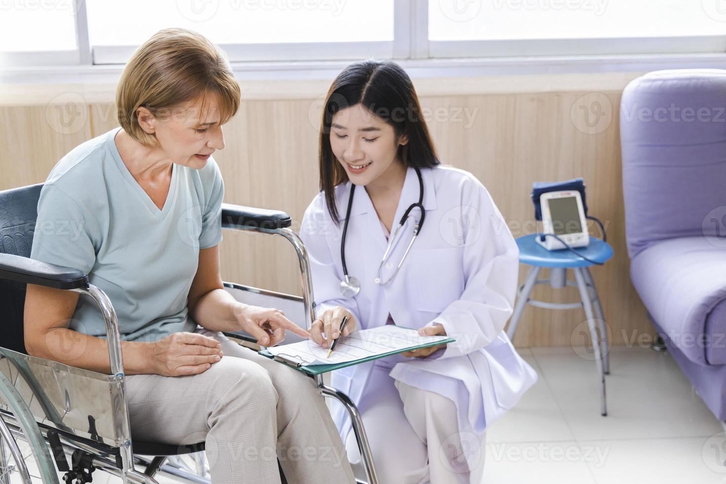 kvinnlig läkare ger råd till den gamla kvinnan patienten genom en tablett på sjukhuset. foto