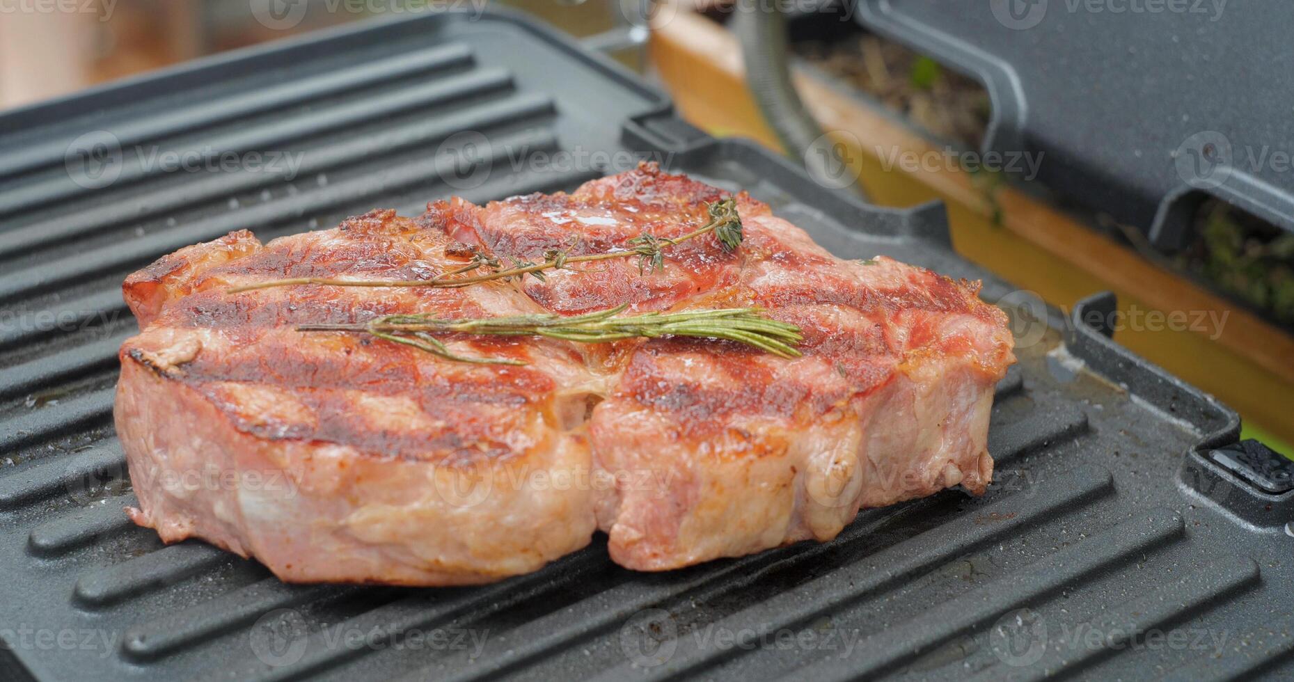 utsökt saftig nötkött biff med rosmarin är kokta på ett elektrisk grill. åldrig främsta sällsynt steka grillning fläskkarré färsk marmor ömhet nötkött. foto