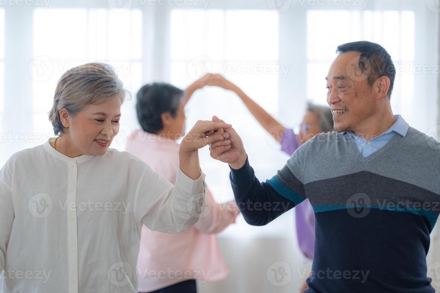 asiatisk äldre manlig och honor människor dansa med deras partners på en dans golv i levande Plats. Lycklig äldre par utför skaffa sig träning. glad sorglös pensionerad senior vänner njuter avslappning foto