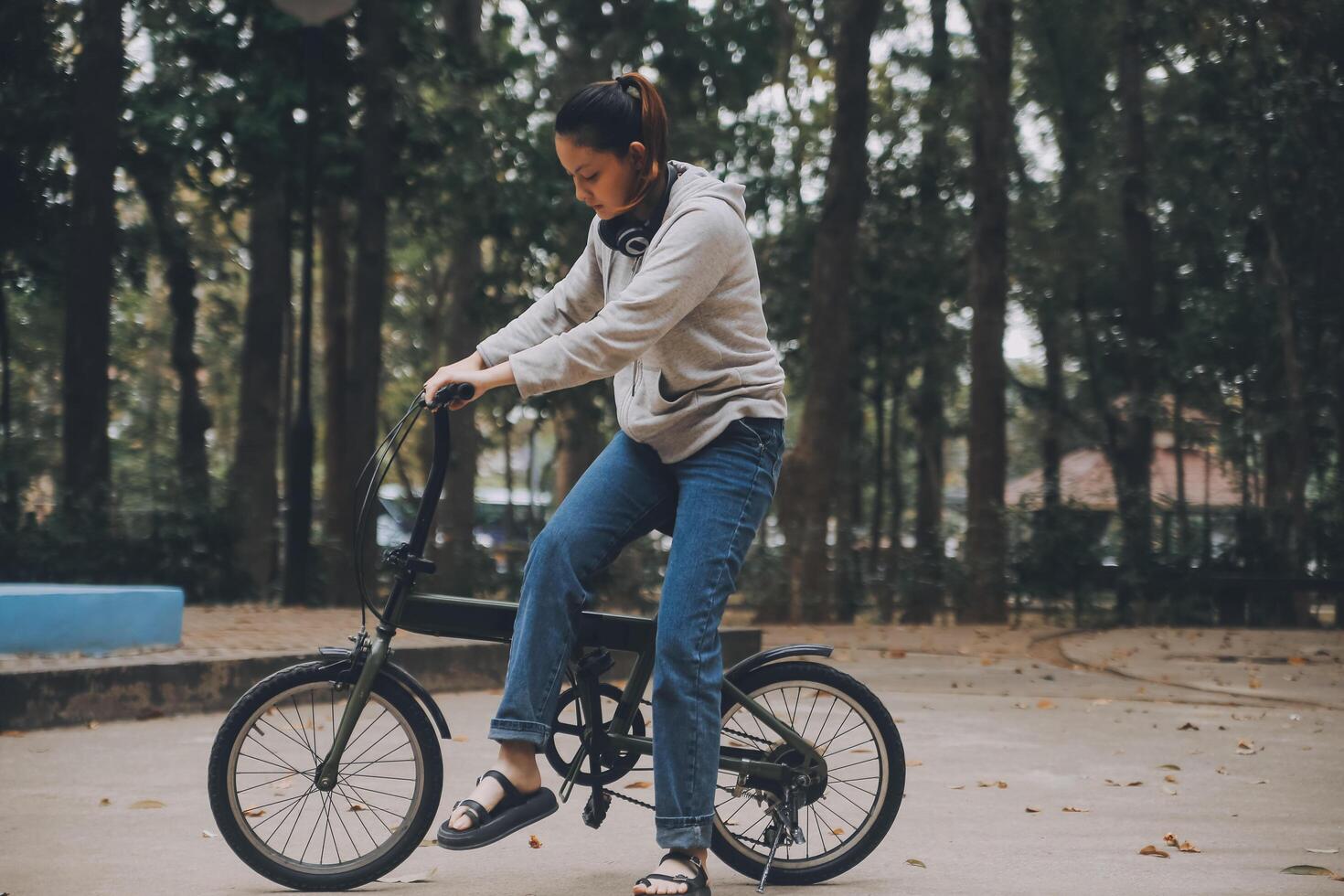 Lycklig asiatisk ung kvinna promenad och rida cykel i parkera, gata stad henne leende använder sig av cykel av transport, eco vänlig, människor livsstil begrepp. foto