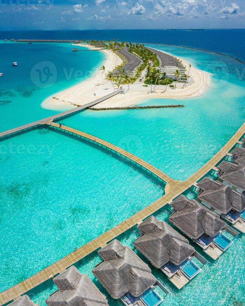 Flygfoto över ön Maldiverna, lyxig semesterort för vattenvillor och träpir. vacker himmel och hav lagun strand bakgrund. sommarsemester semester och resekoncept. paradis flyglandskap panorama foto