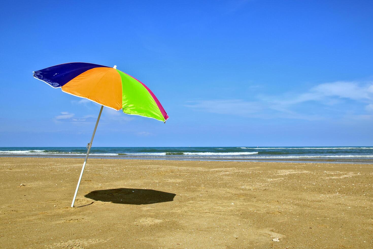 färgrik paraplyer uppsättning i de sand med klar himmel och tömma hav. foto