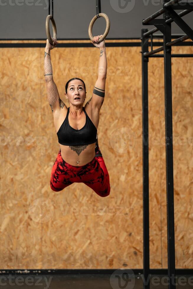 sportigt kvinna hängande från olympic ringar medan arbetssätt ut foto