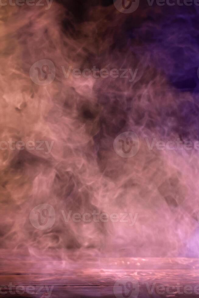 konceptuell bild av flerfärgad rök isolerad på mörk svart bakgrund och träbord. foto