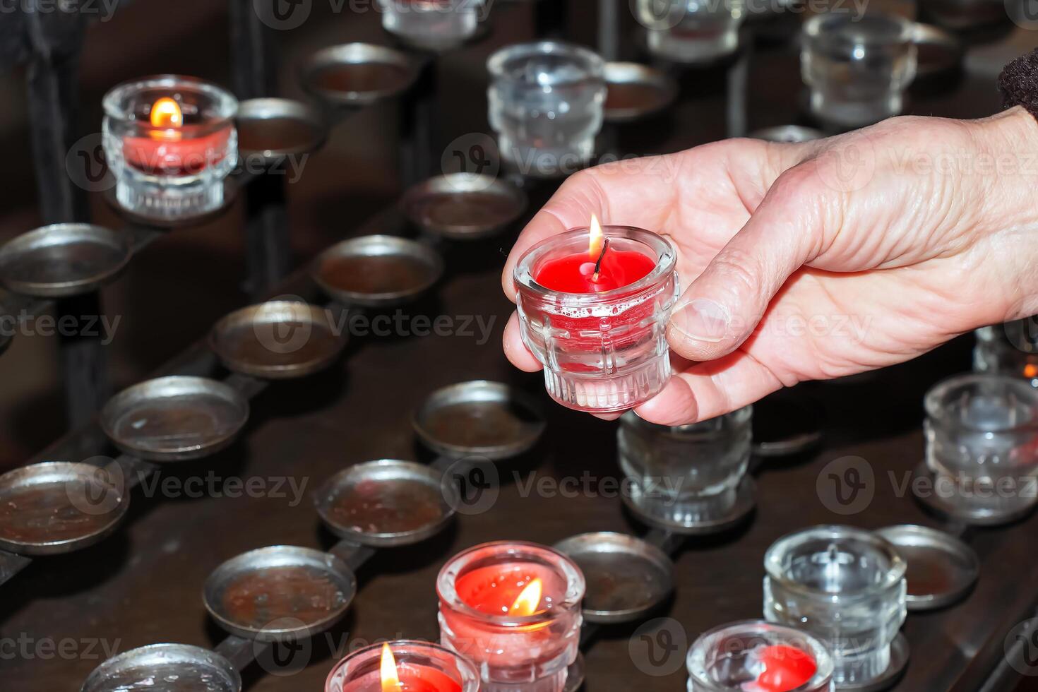 bön ljus inuti en katolik kyrka. en kvinnas hand innehar en ljus. foto