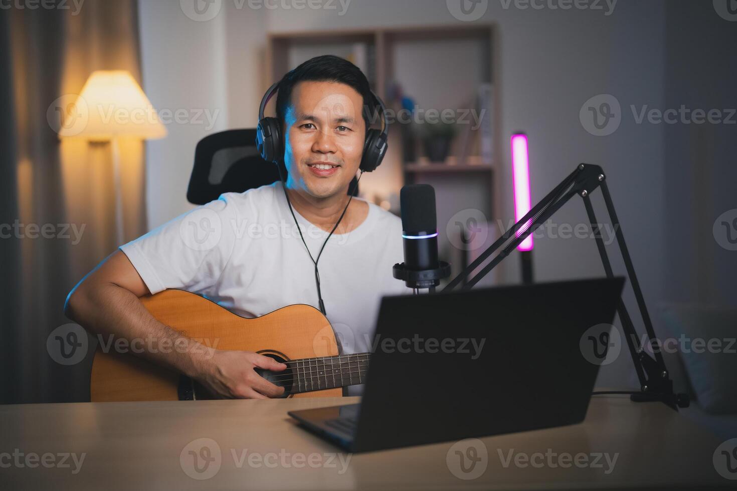 asiatisk man leva strömning prestanda spelar gitarr och sjunga en låt. asiatisk man undervisning gitarr och sång uppkopplad. musiker inspelning musik med bärbar dator och spelar akustisk gitarr. foto