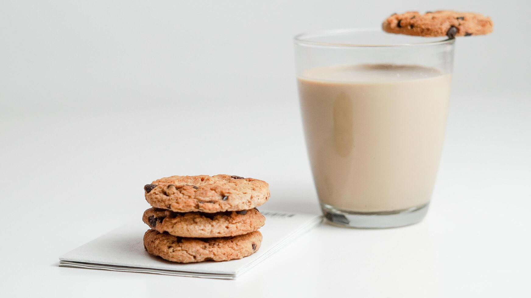 choklad chip småkakor och en glas av mjölk kaffe på en vit bakgrund foto