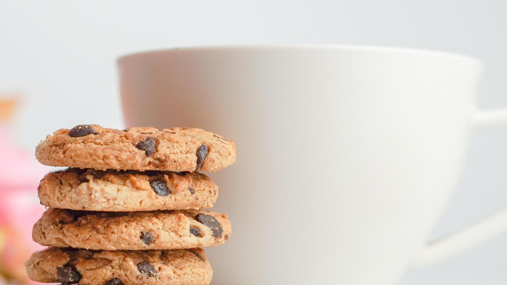 choklad chip småkakor och en glas av mjölk kaffe på en vit bakgrund foto