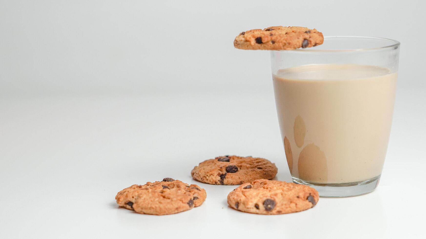 choklad chip småkakor och en glas av mjölk kaffe på en vit bakgrund foto