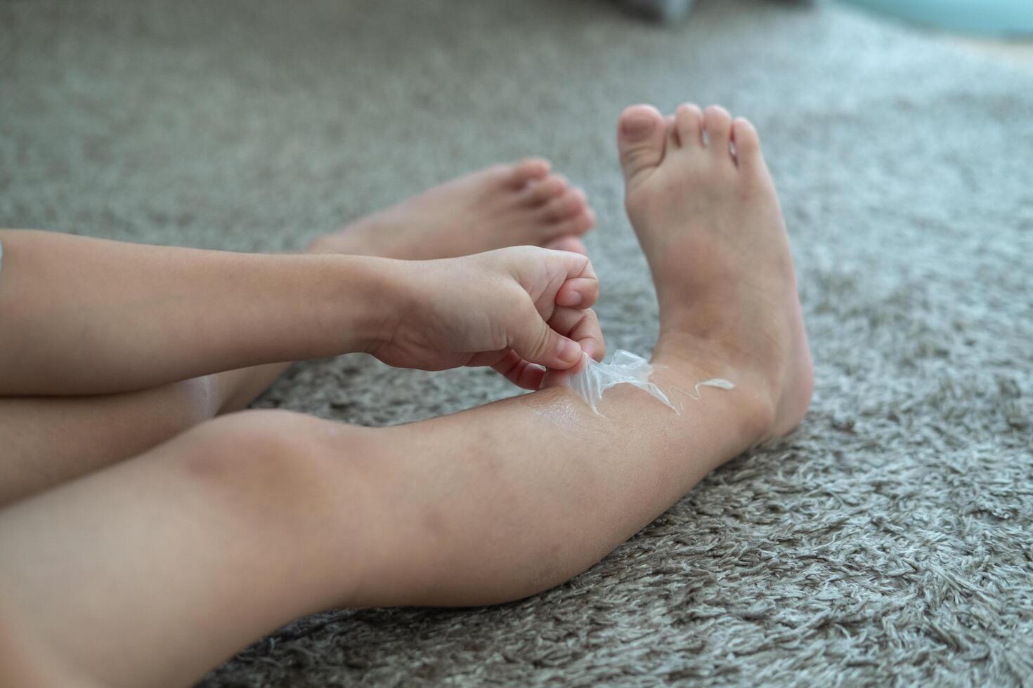 liten asiatisk Pojkar händer peeling av torr hud på hans ben. hud problem. foto