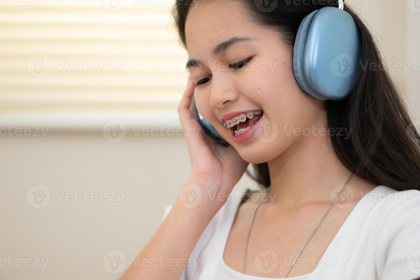 porträtt av Tonårs flicka lyssnande till musik med hörlurar på Hem. foto