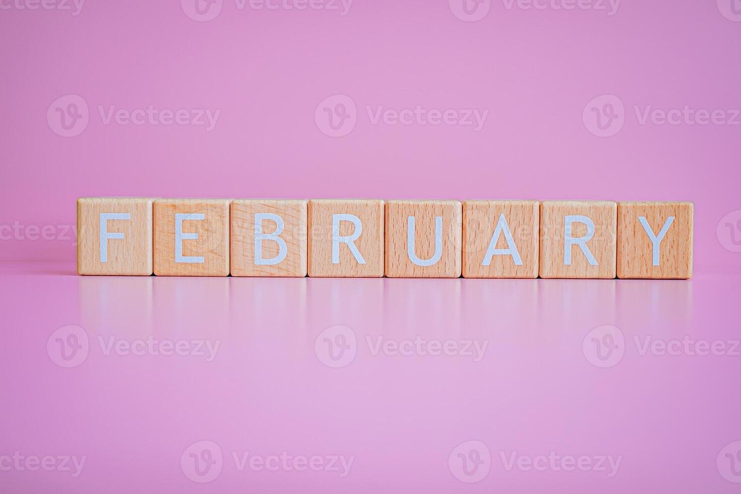 trä- block form de text februari mot en rosa bakgrund. foto