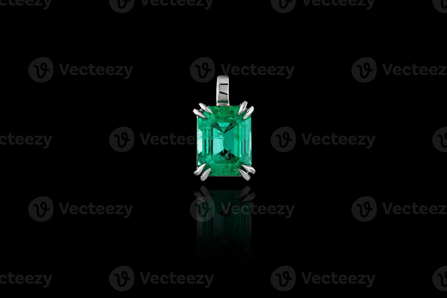 skön hängsmycke med ett smaragd- och en diamant med en kedja på en svart bakgrund foto