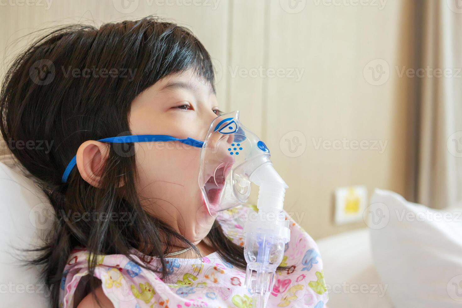 sjuk liten asiatisk flicka inandning med nebulisator för respiratorisk behandling foto
