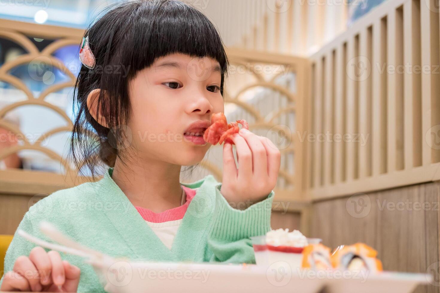 söt liten asiatisk barn flicka äter mat foto