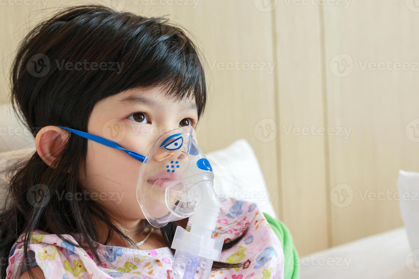 sjuk liten asiatisk flicka inandning med nebulisator för respiratorisk behandling foto