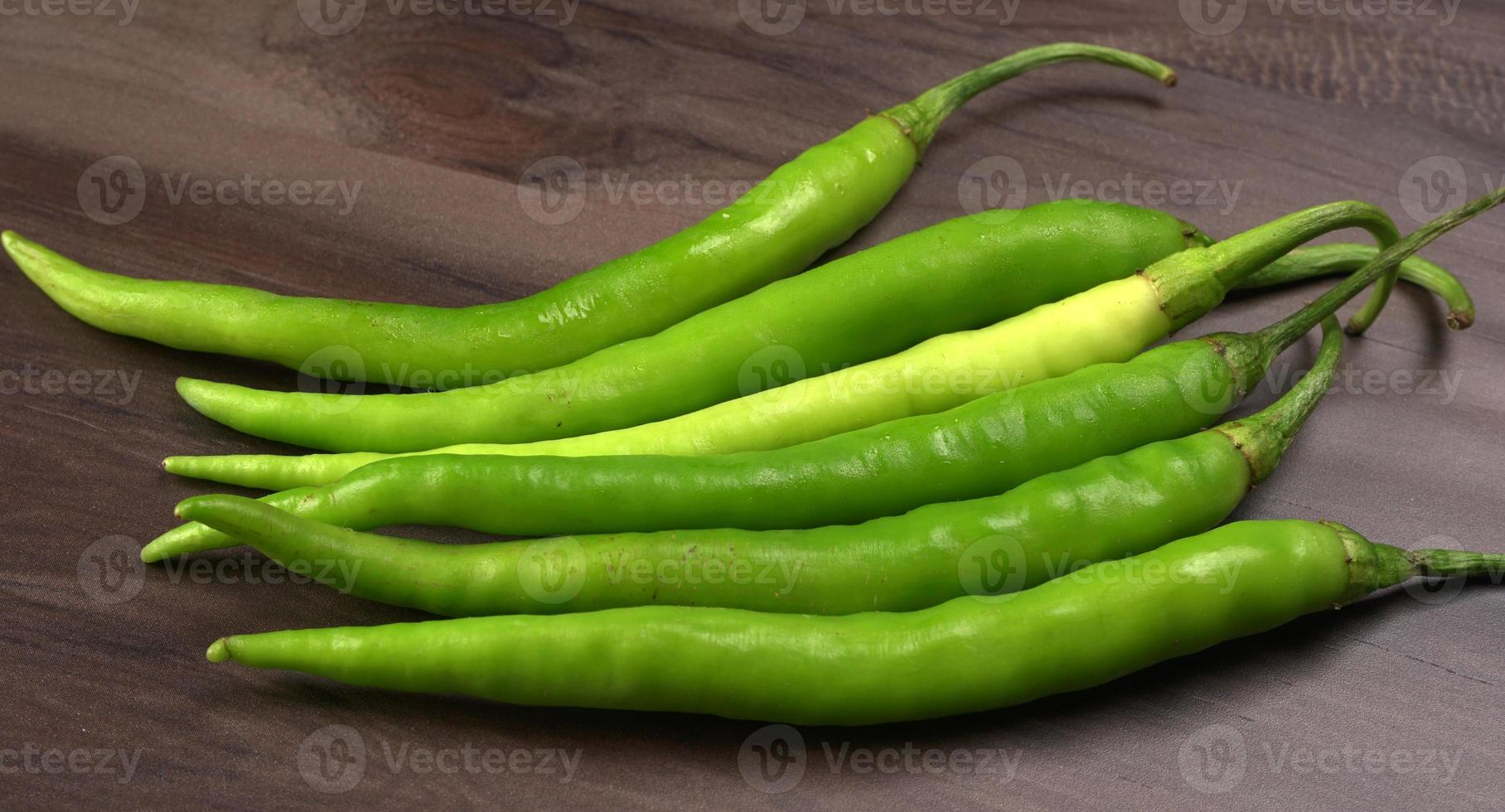 färska långa indiska gröna chili på trä bakgrund. foto