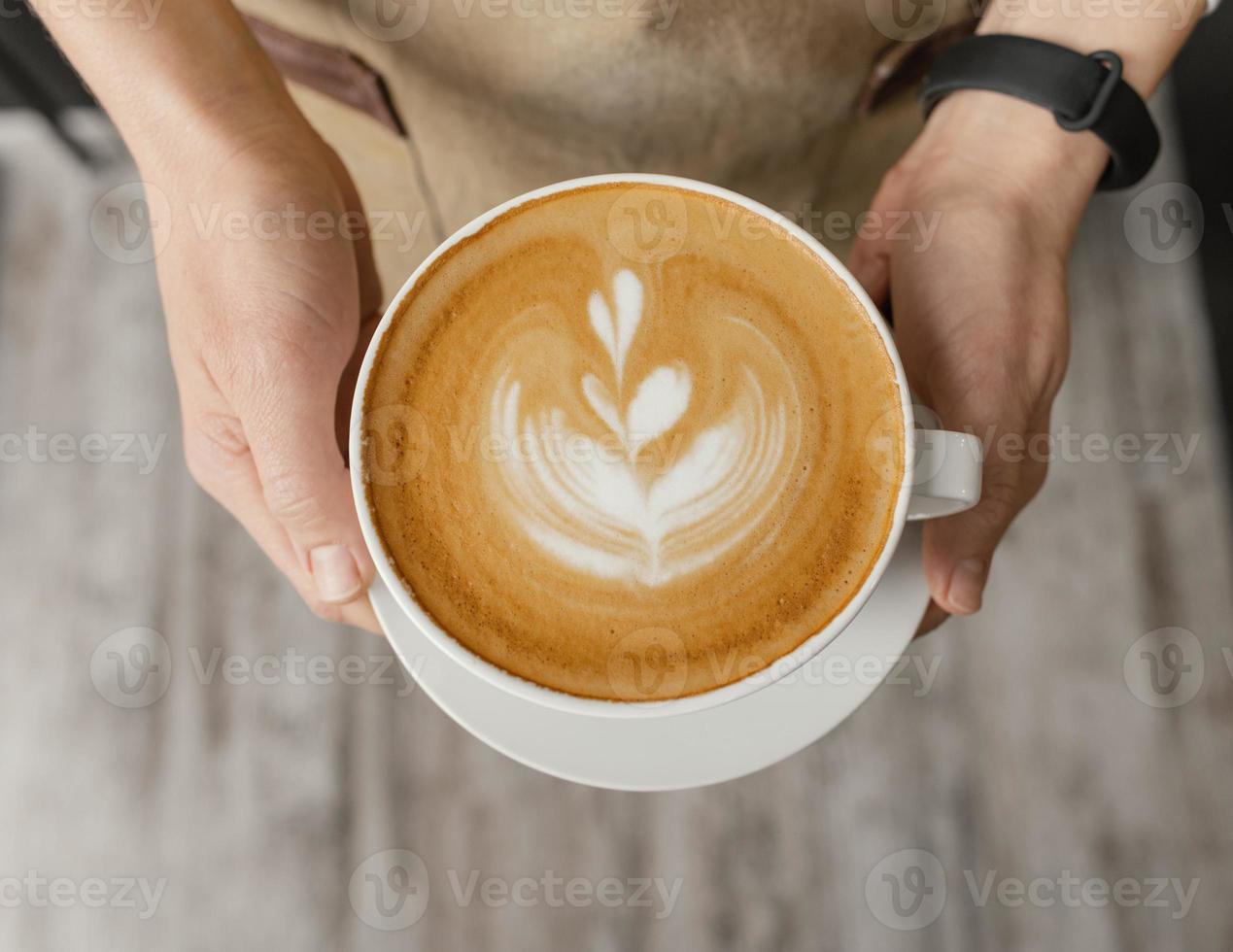 ovanifrån kvinnlig barista håller dekorerade kopp kaffe händer foto