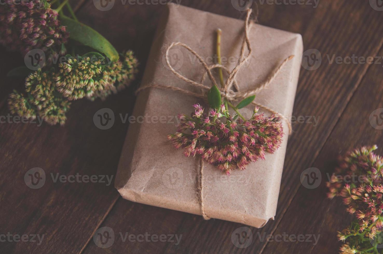 hemgjord presentförpackning inslagen i kraftpapper och rosa blommor foto