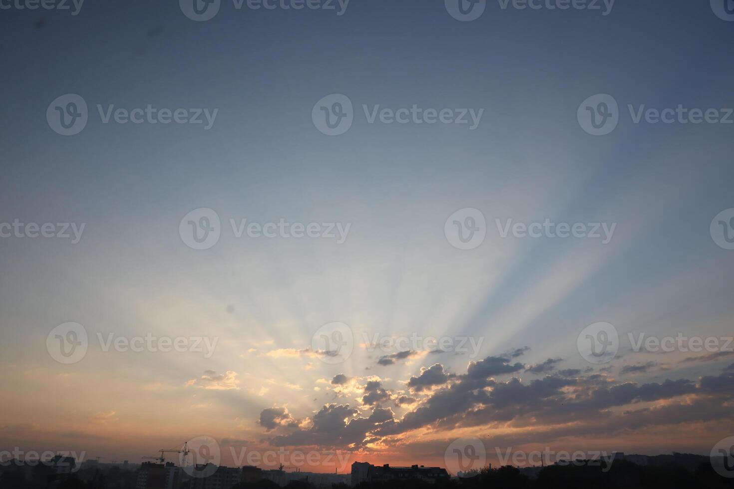 skön soluppgång med värma orange solljus och balkar genom blå himmel foto