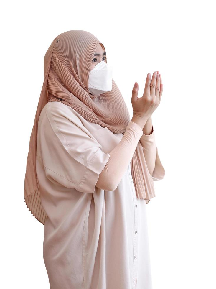 muslimsk flicka som bär en kirurgisk mask ber på vit bakgrund foto