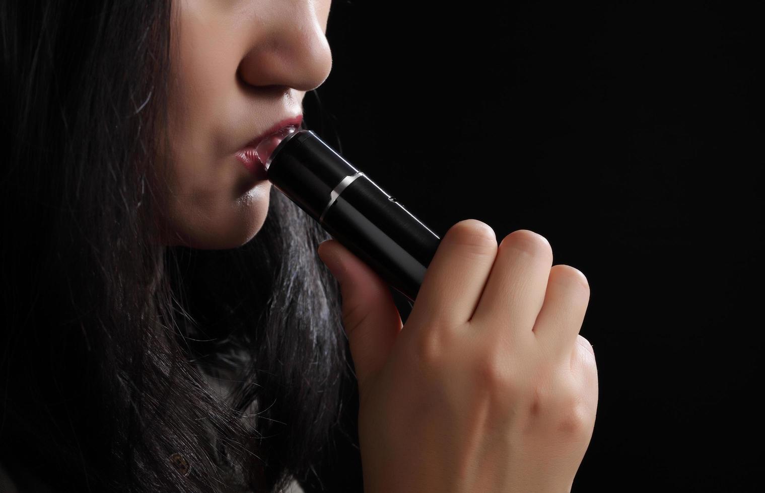 närbild ung kvinna som röker e-cigarett på svart bakgrund foto