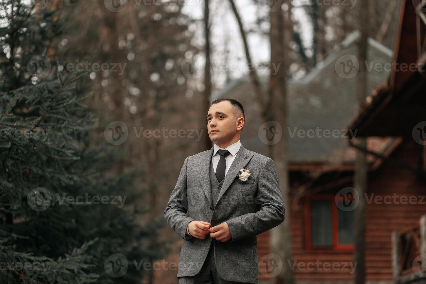 de brudgum i en grå kostym poser under en promenad i de skog. företag stil. vinter- bröllop. foto