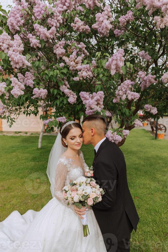 bröllop. kärlek och par i trädgård för bröllop. fira de ceremoni och engagemang. spara de datum. förtroende. de brud och brudgum omfamning mot de bakgrund av en vår blomning träd. foto