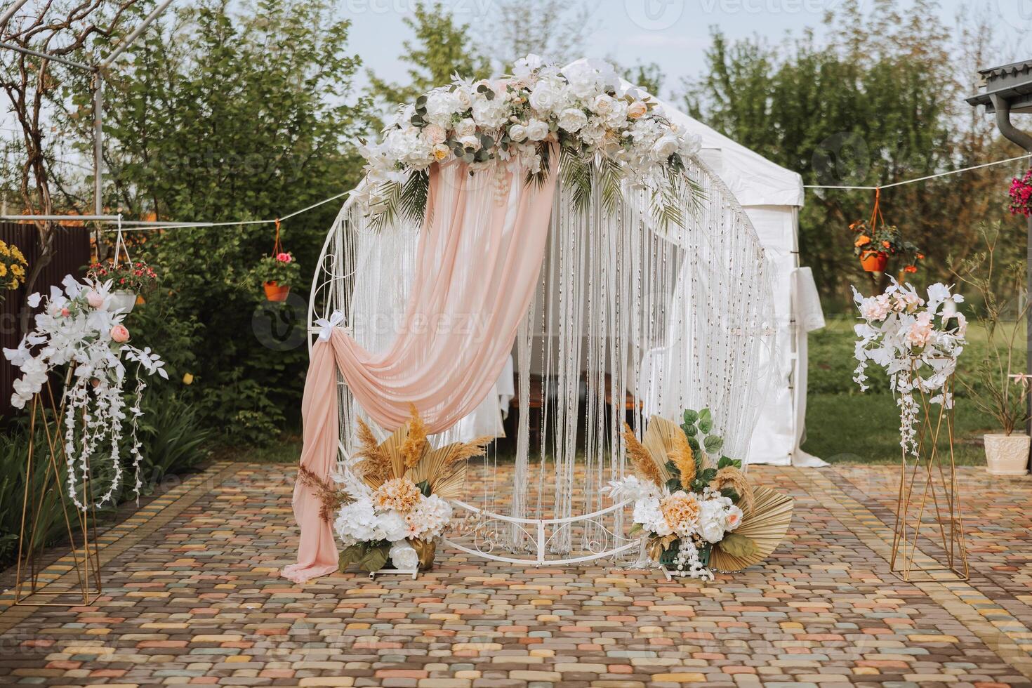 bröllop. bröllop ceremoni. ark. ett båge dekorerad med rosa och vit blommor står i de gård, i de område av de bröllop ceremoni foto