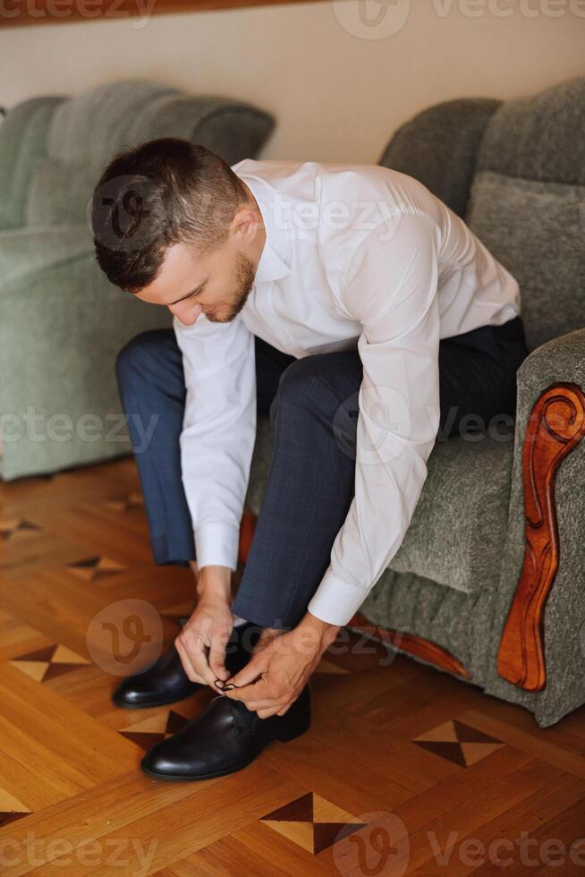 en mannens händer slips de skosnören av hans ny skor. människor, företag, mode och Skodon begrepp - närbild av en mannens ben och händer kvitt skosnören. de brudgum sätter på hans skor. foto