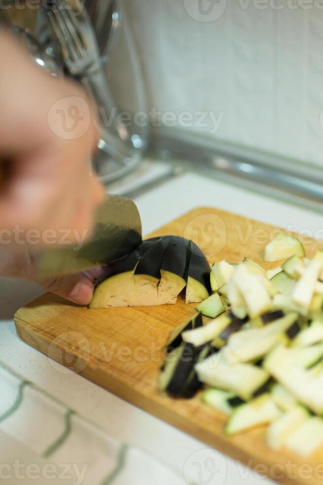 caucasian man skärande äggplanta på en trä- tabell foto