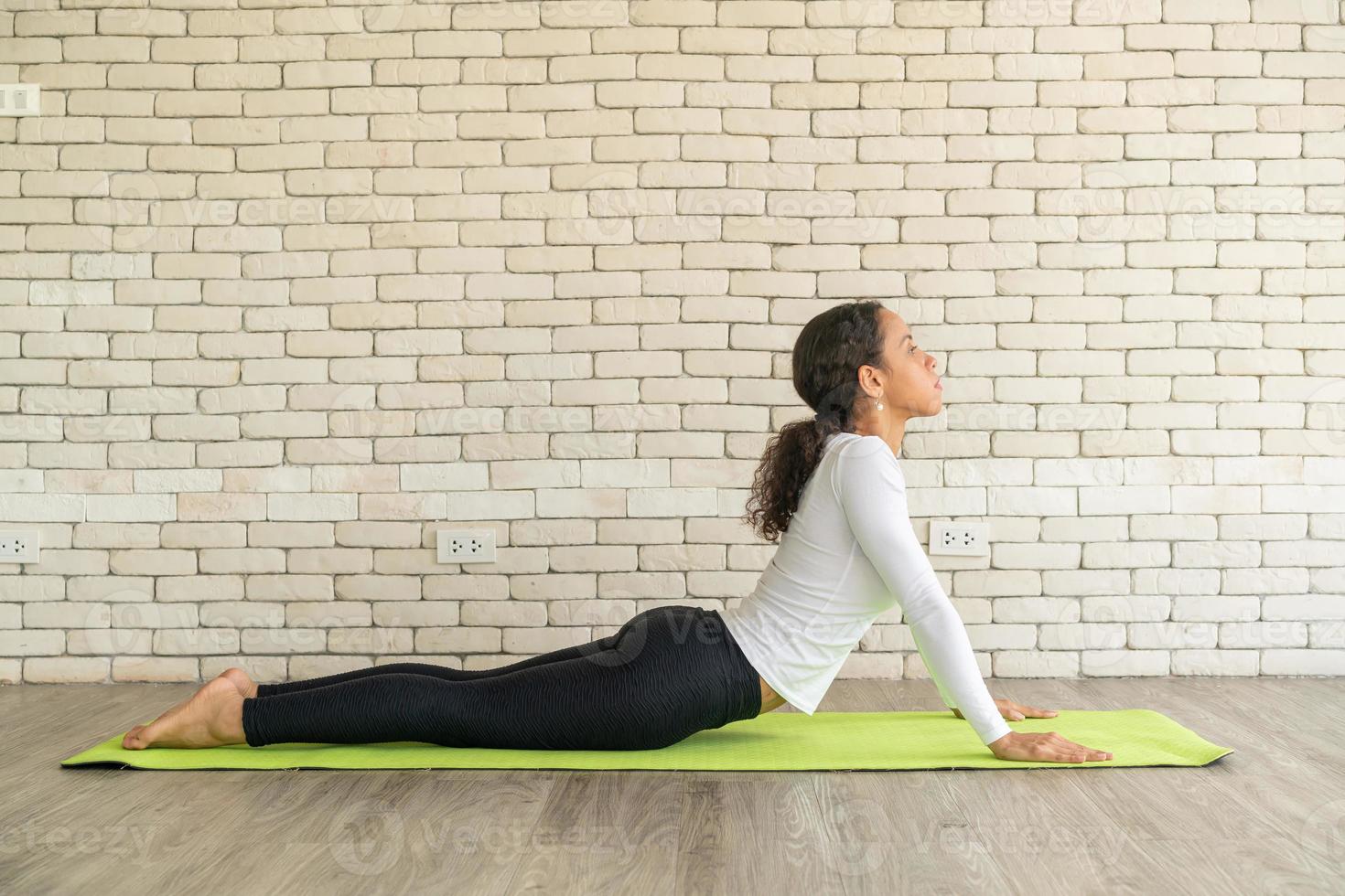 latinsk kvinna utövar yoga på mattan foto