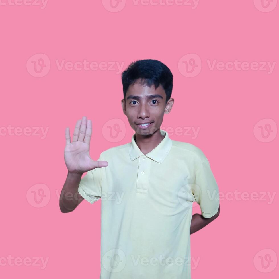 ung asiatisk man händer sluta. med en allvarlig ansikte bär en gul t-shirt, isolerat på en rosa bakgrund foto