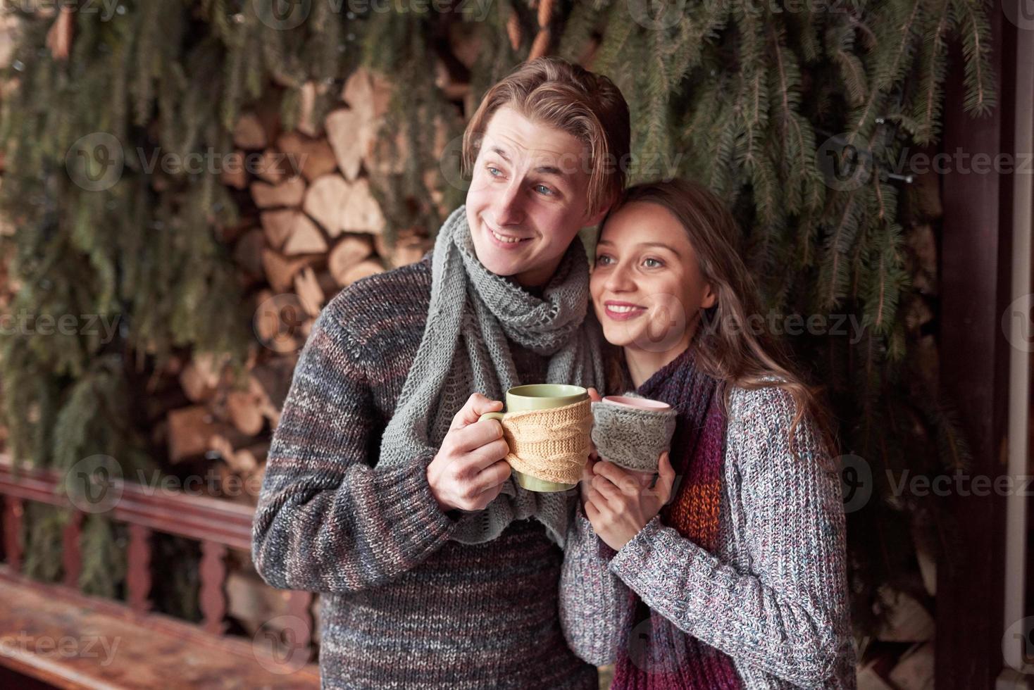 ungt par som äter frukost i en romantisk stuga utomhus på vintern. vintersemester och semester. julpar av lycklig man och kvinna dricker varmt vin. par i kärlek foto