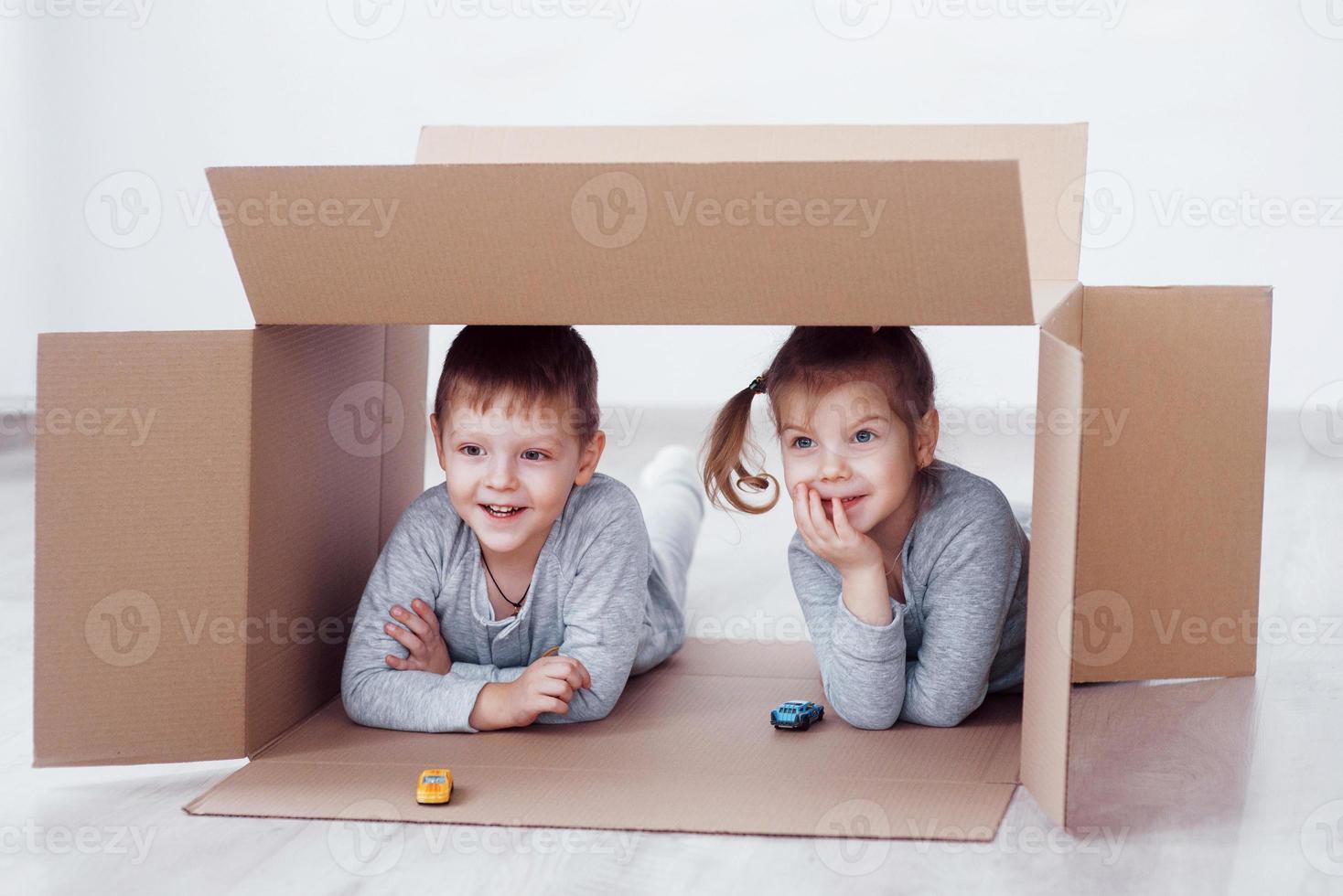 babybror och barnsyster som leker i kartonger i barnkammaren foto