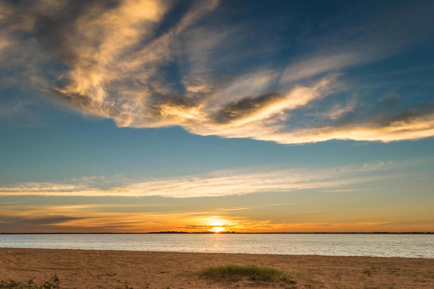 landskap av skön solnedgång med moln på de rutt och sedan på de strand med handflatan träd runt om foto