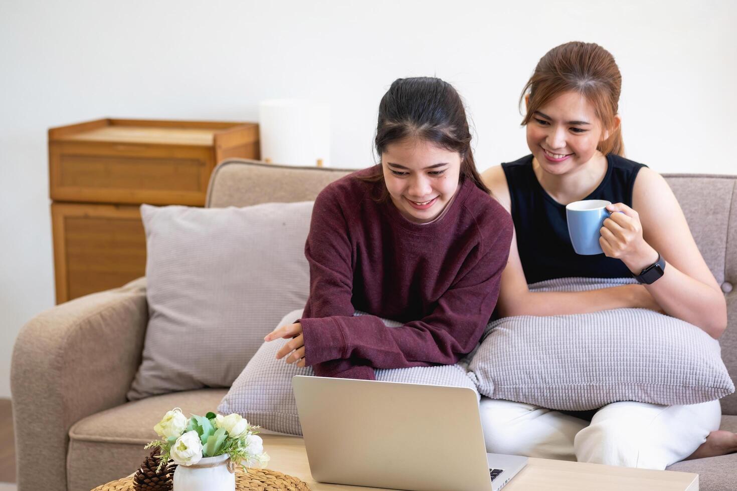 avslappnad ung asiatisk kvinna njuter avslappning på en bekväm soffa på Hem. de skön flicka lugnt slappnar av och andas färsk luft i de hus. Kolla på bio och social nätverk. foto