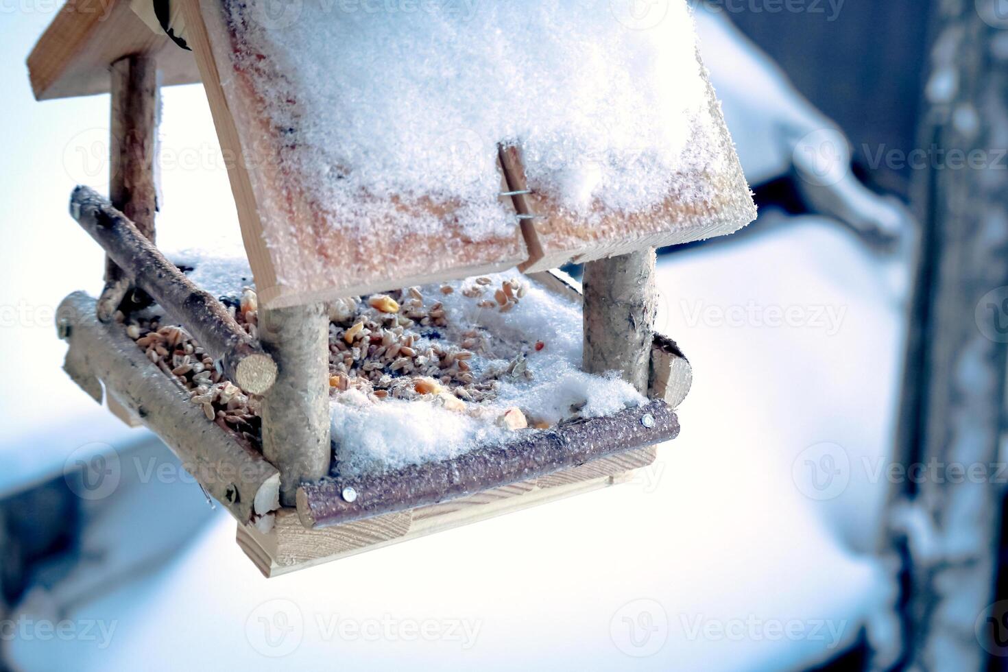 handgjort små fågel matare med frön för fåglar hängande på en fönster täckt i snö foto