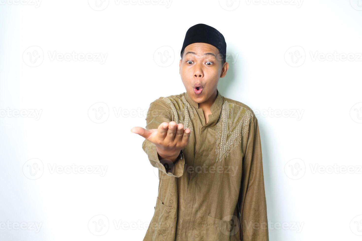 överraskad asiatisk muslim man presenter på kamera med öppen handflatan isolerat på vit bakgrund foto