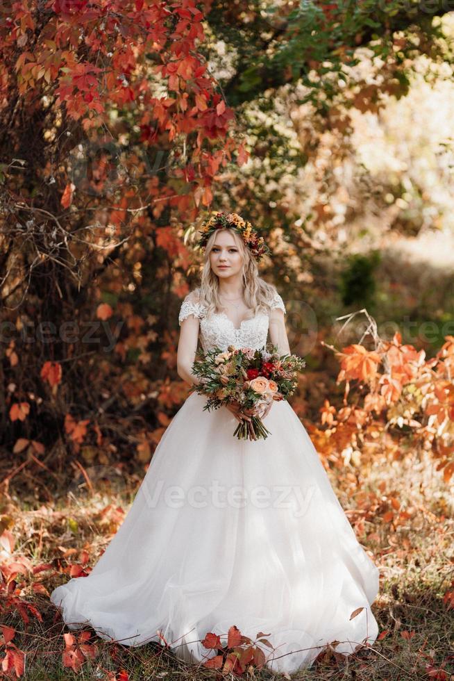 blond flicka i en bröllopsklänning i höstskogen foto