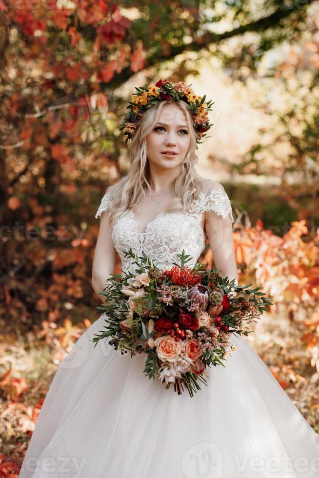 blond flicka i en bröllopsklänning i höstskogen foto