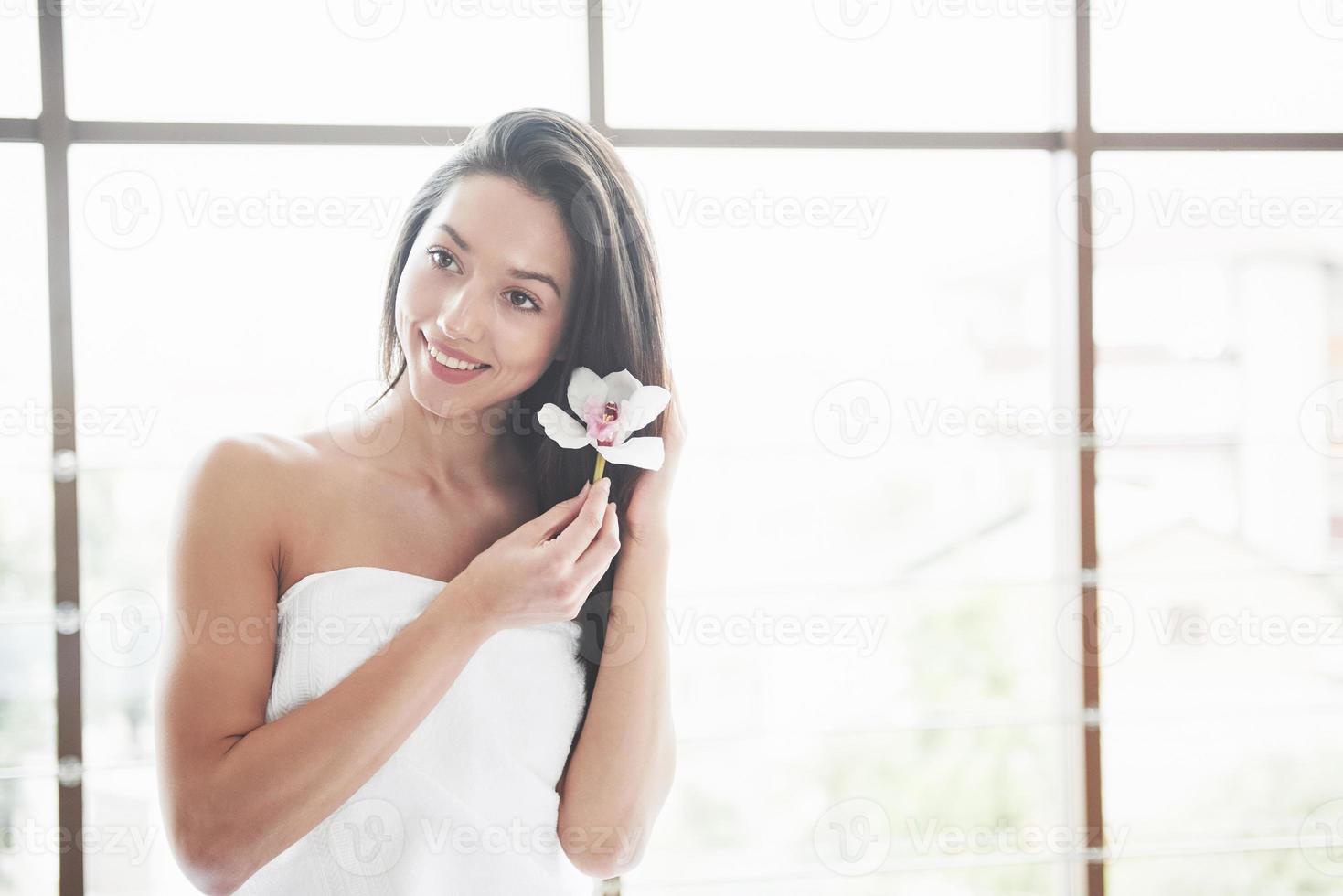 vacker flicka i en handduk med en orkidé, avslappningsmassage väntar. foto
