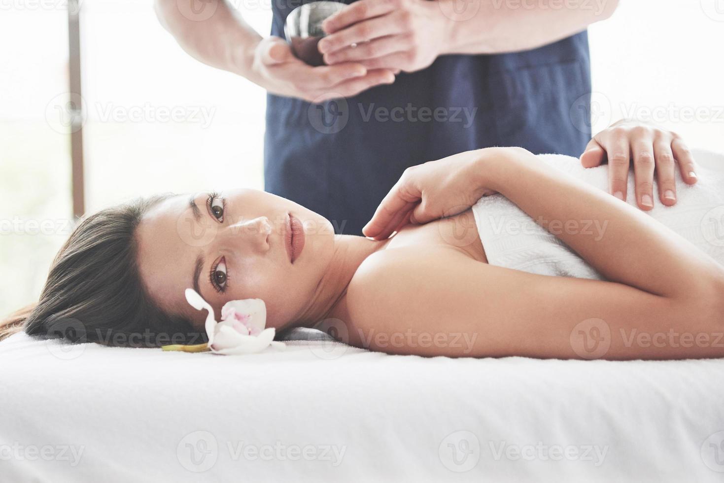 vacker kvinna liggande på massagebänk i spa. foto