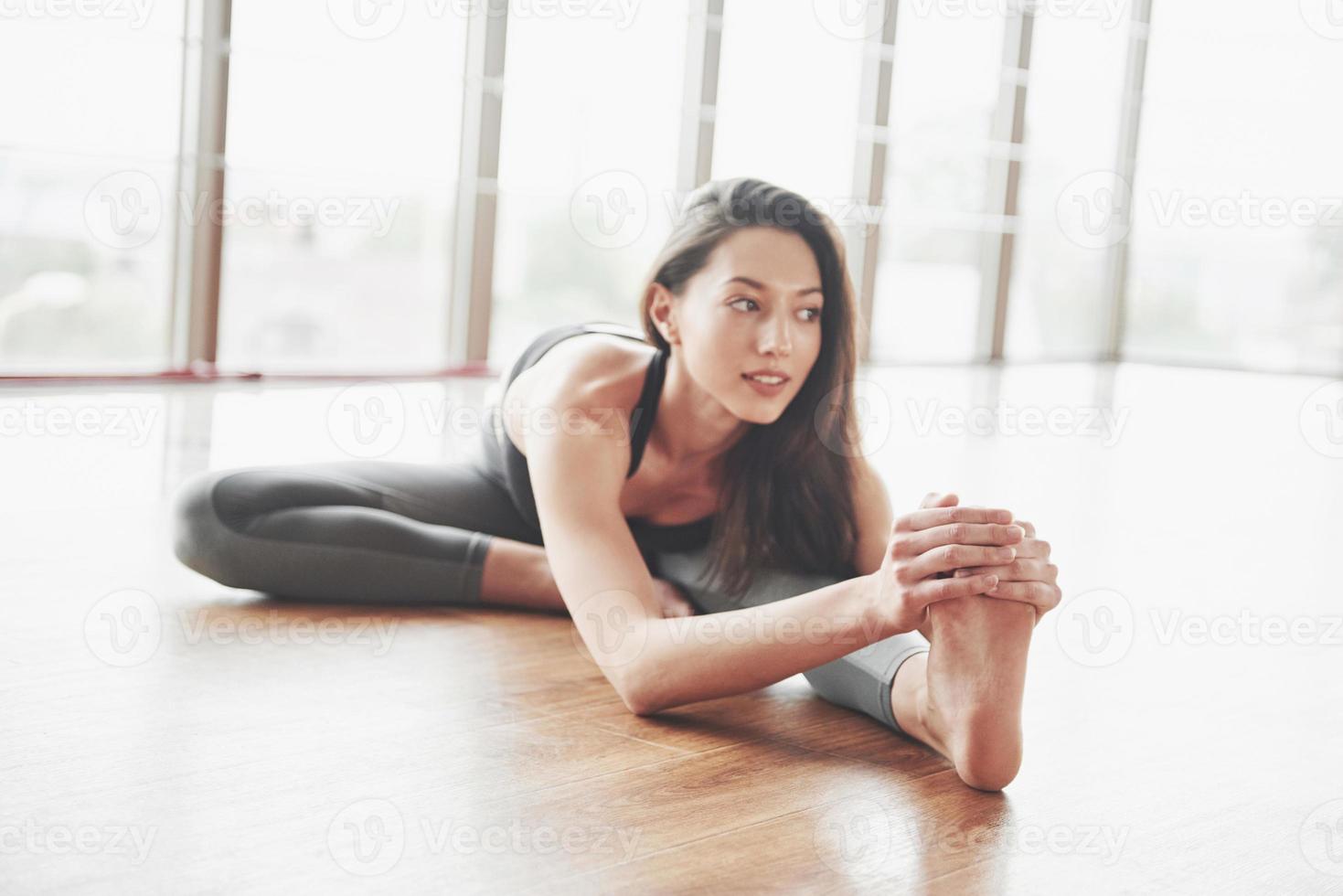 stretching en gymnast kvinna gör en split, ett garn i ett gym. foto