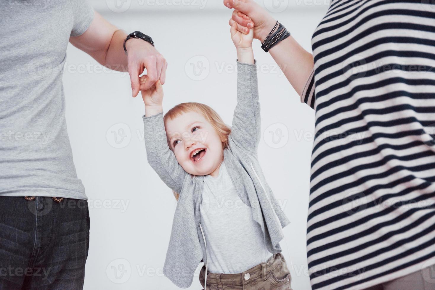 lycklig familj har roligt hemma. mamma, pappa och lilla håller varandra i hand foto