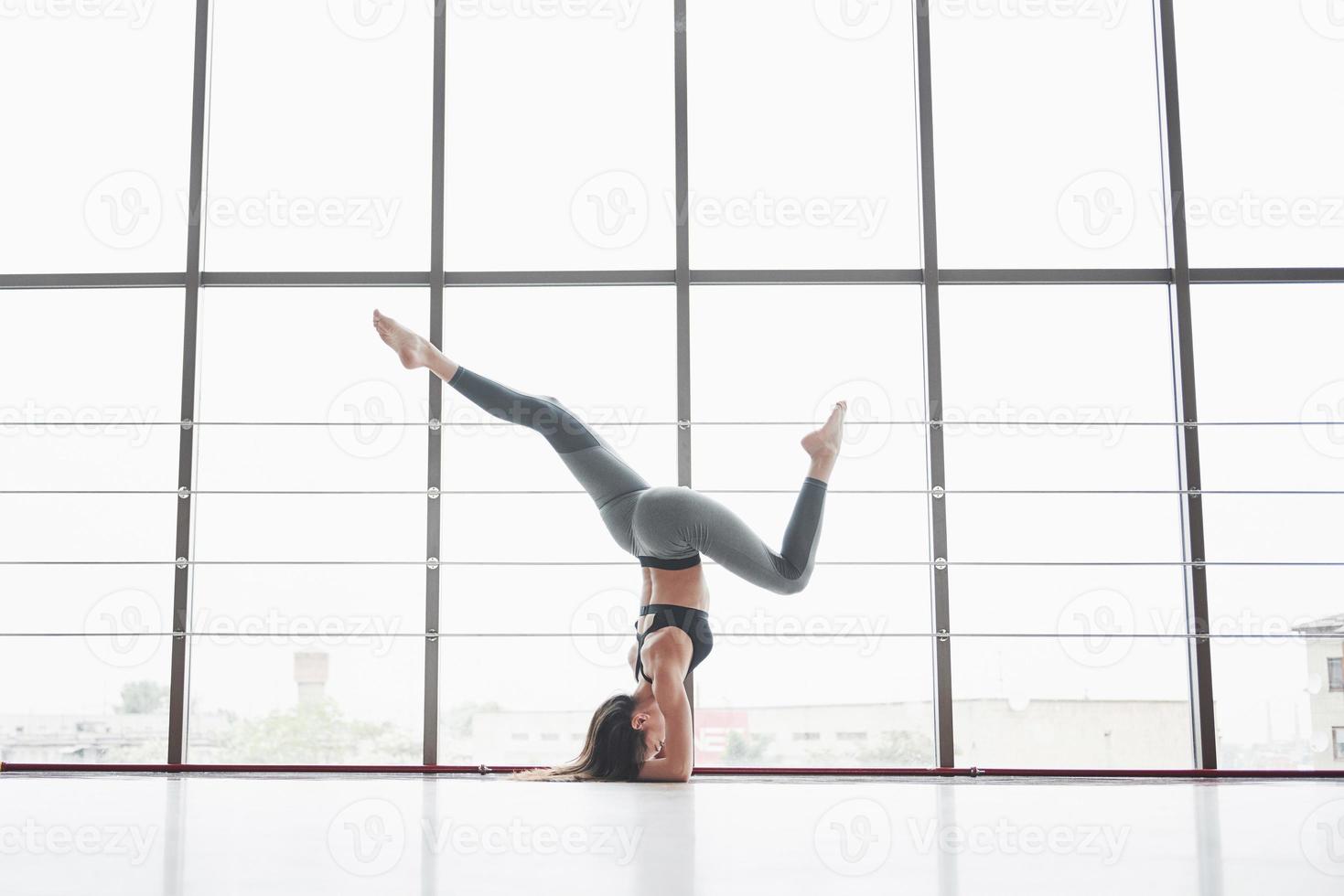 en idrottskvinna som håller på med yogaklasser och sträcker på benen nära det stora fönstret foto