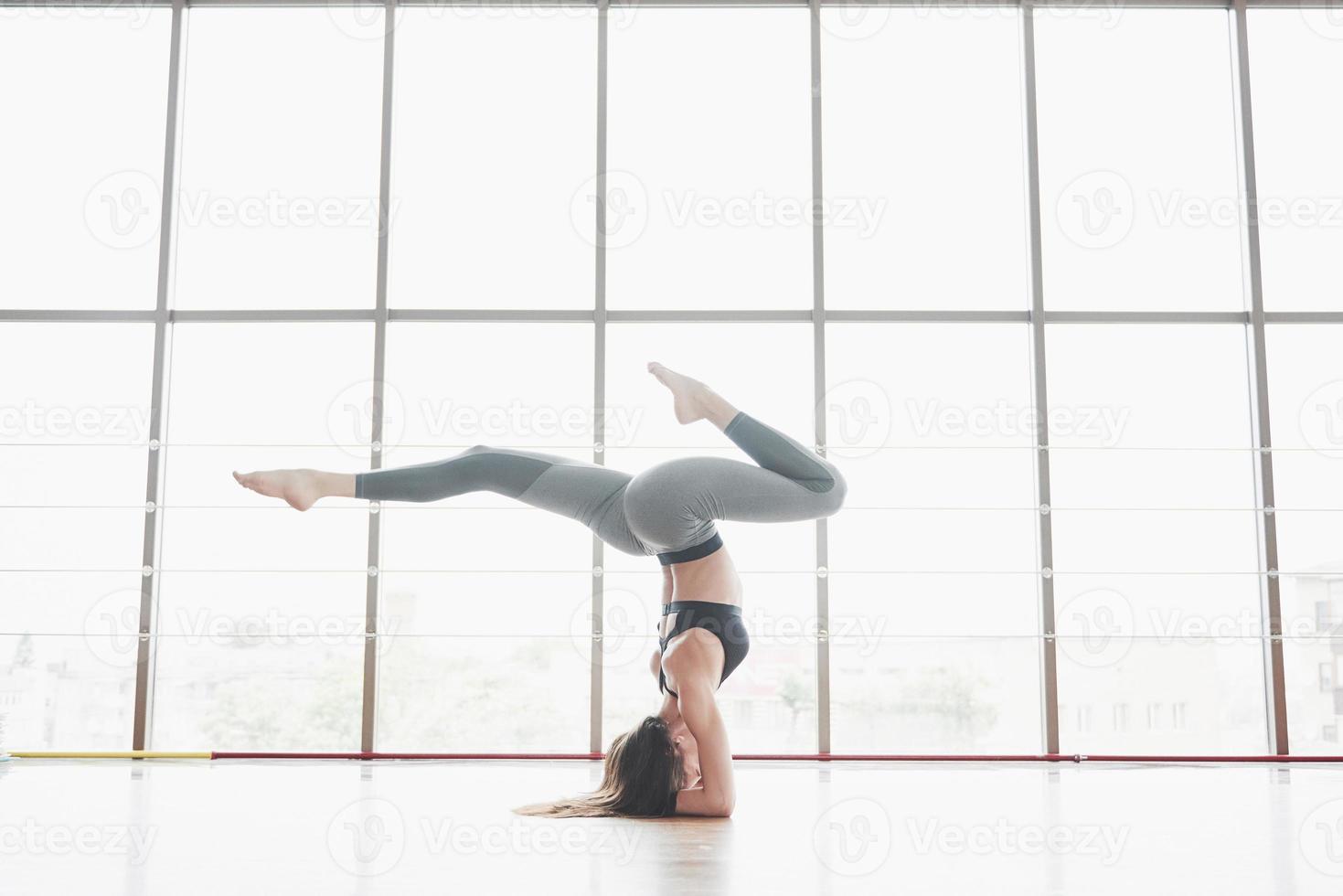 en idrottskvinna som håller på med yogaklasser och sträcker på benen nära det stora fönstret foto