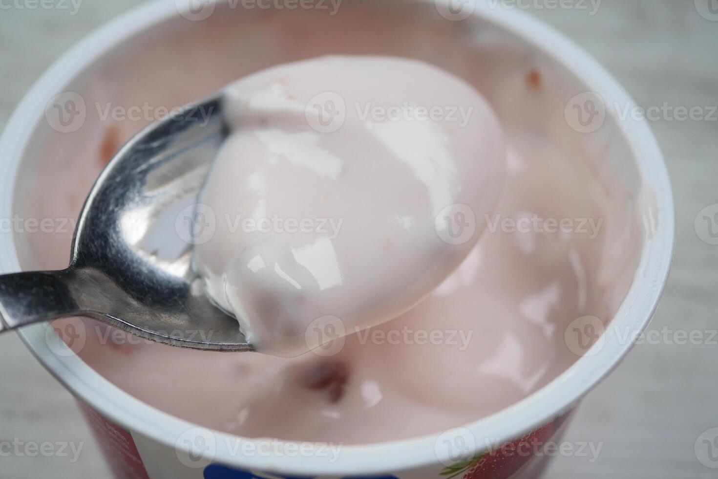 sked plockar färsk yoghurt i en plast behållare foto