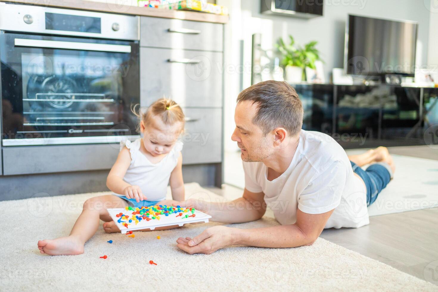 söt liten flicka spelar med svamp nagel mosaik. far och bebis spelar tillsammans begrepp. hobby och fritid tid. foto